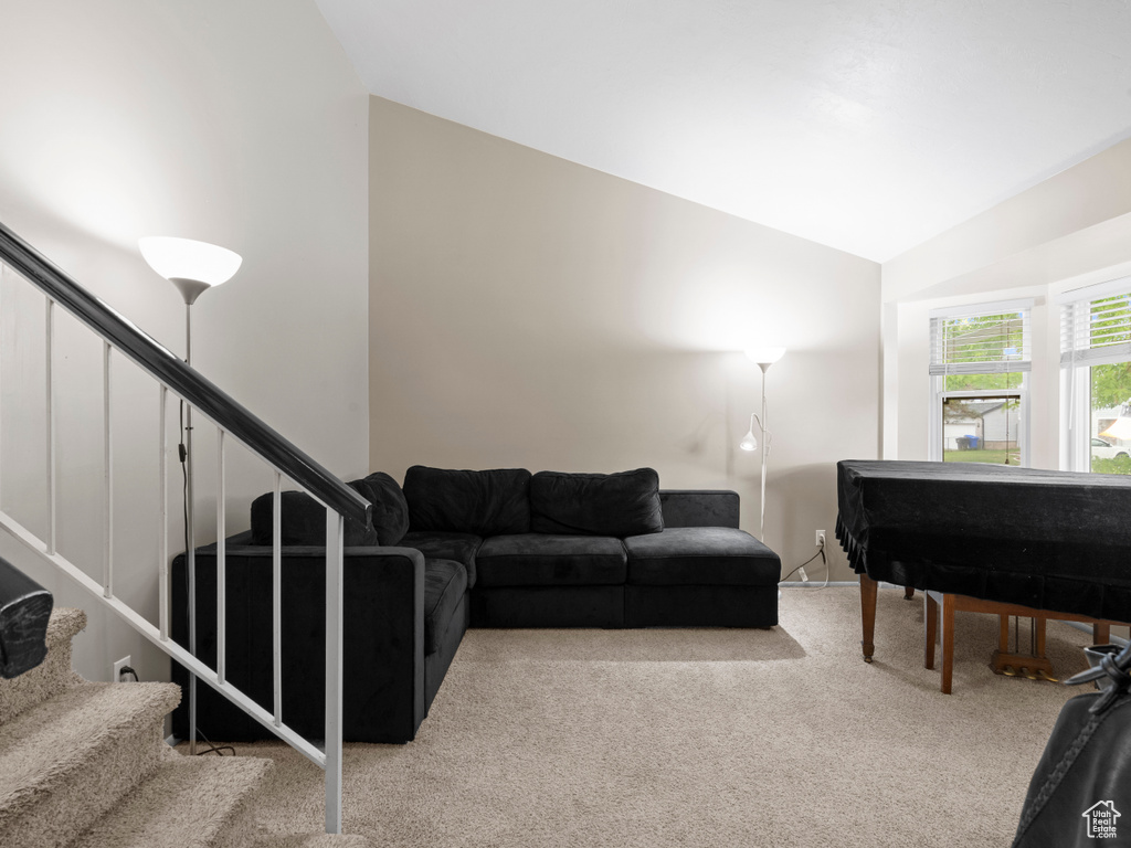 Carpeted living area featuring lofted ceiling and stairs