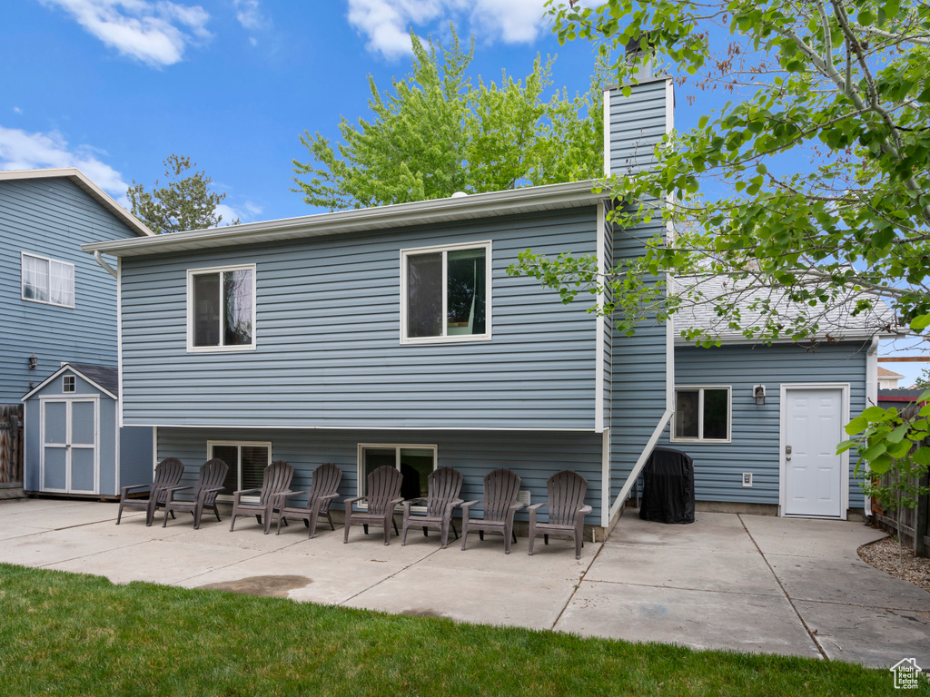 Back of property featuring a patio area, a storage shed, a chimney, and an outdoor structure