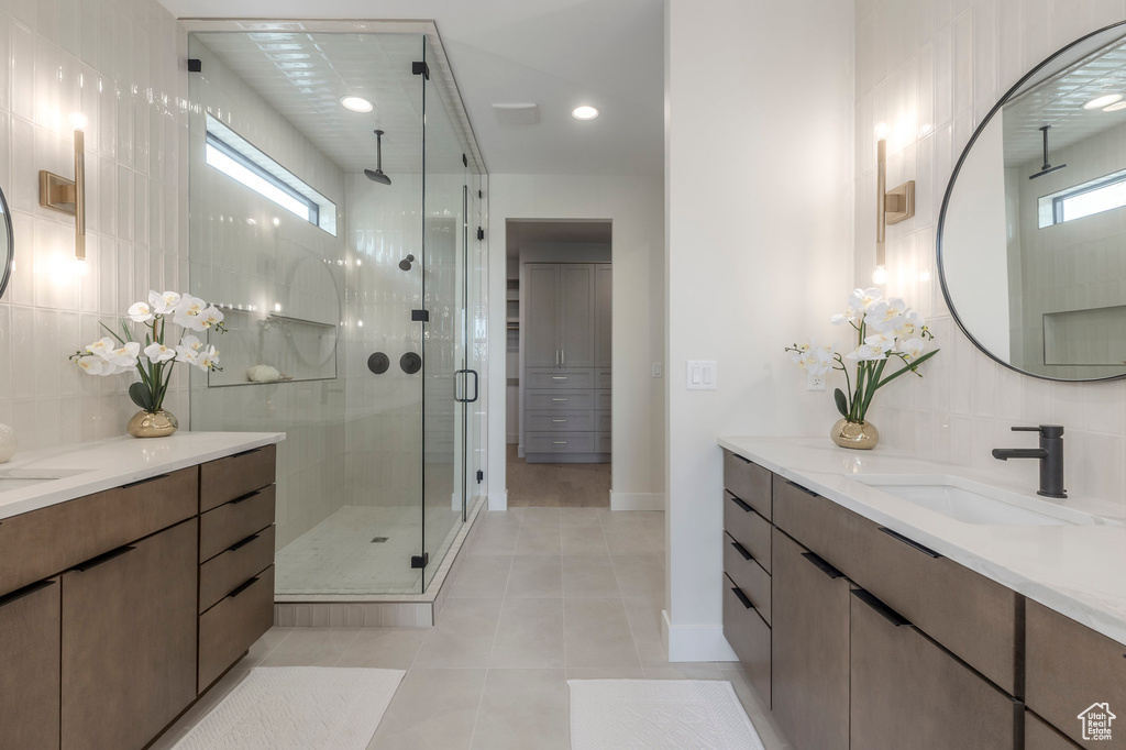 Full bath with baseboards, a shower stall, tile patterned flooring, decorative backsplash, and vanity