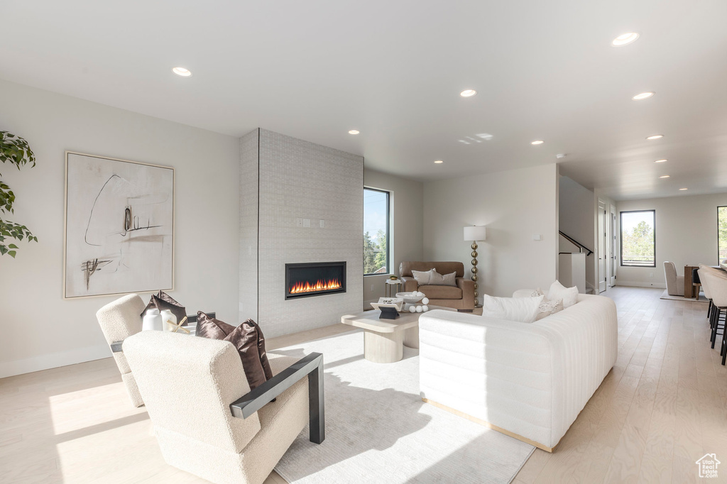 Living area featuring light wood-style floors, stairway, a fireplace, and recessed lighting