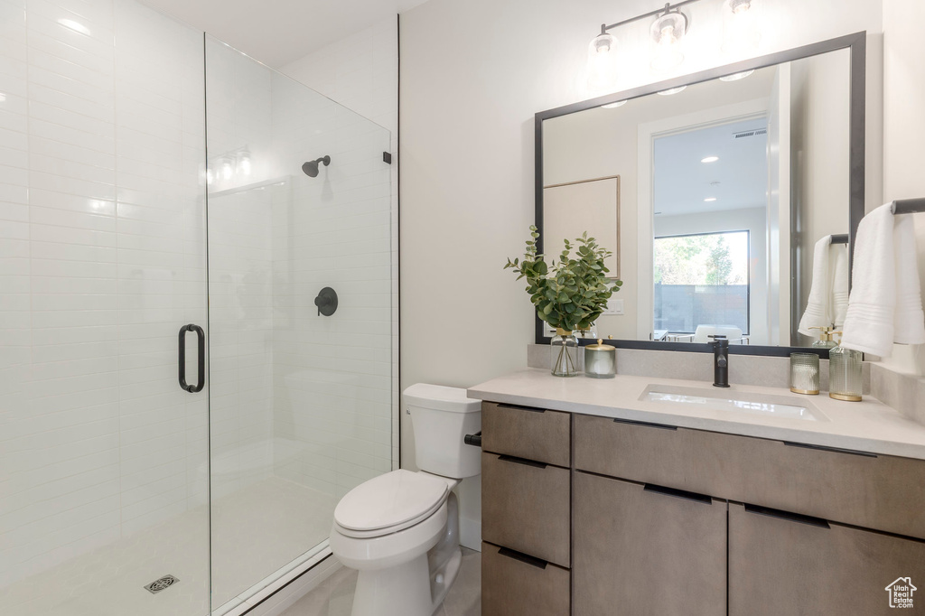 Bathroom with toilet, vanity, and a stall shower