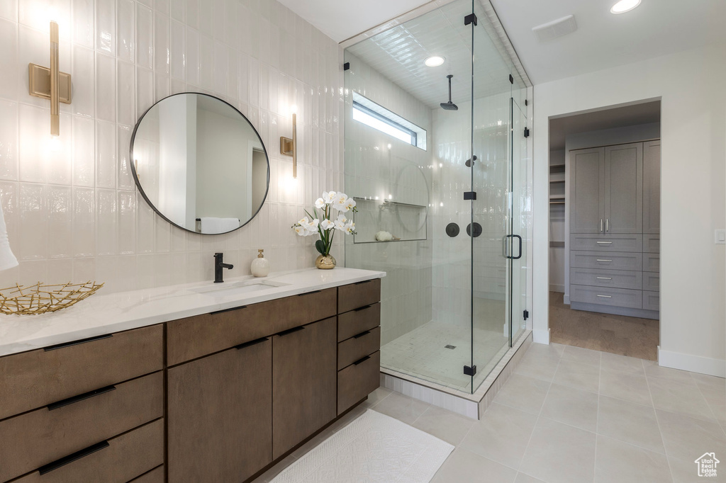 Bathroom featuring tile patterned floors, vanity, tile walls, and a shower stall