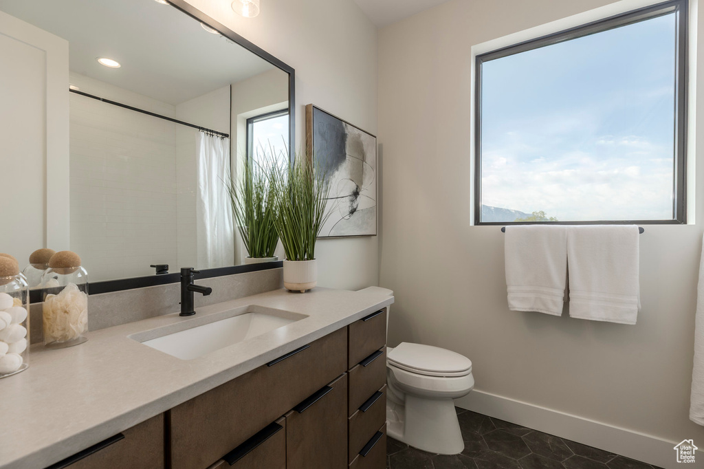 Full bath featuring toilet, a healthy amount of sunlight, and vanity
