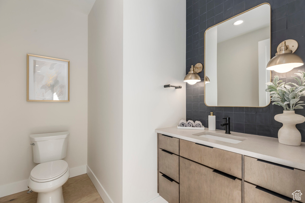 Bathroom featuring recessed lighting, baseboards, toilet, vanity, and backsplash