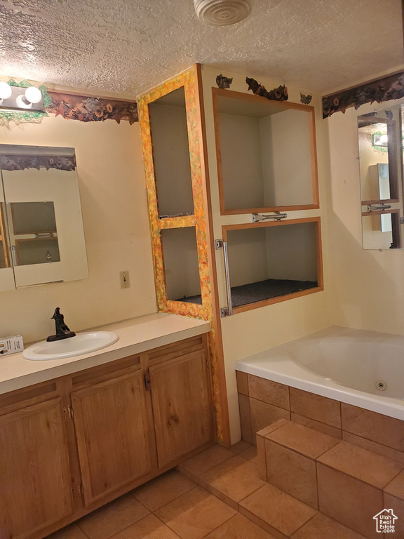 Full bath featuring a textured ceiling, a tub with jets, tile patterned floors, and vanity