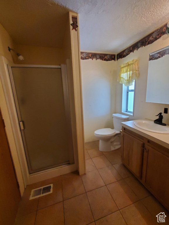 Full bath with tile patterned flooring, toilet, a textured ceiling, a shower stall, and visible vents