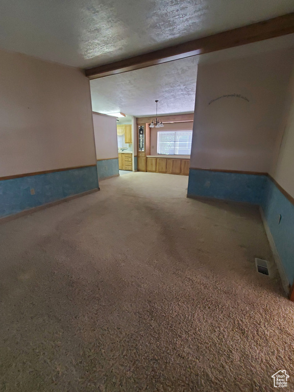 Unfurnished room with baseboards, carpet, a textured ceiling, and a chandelier