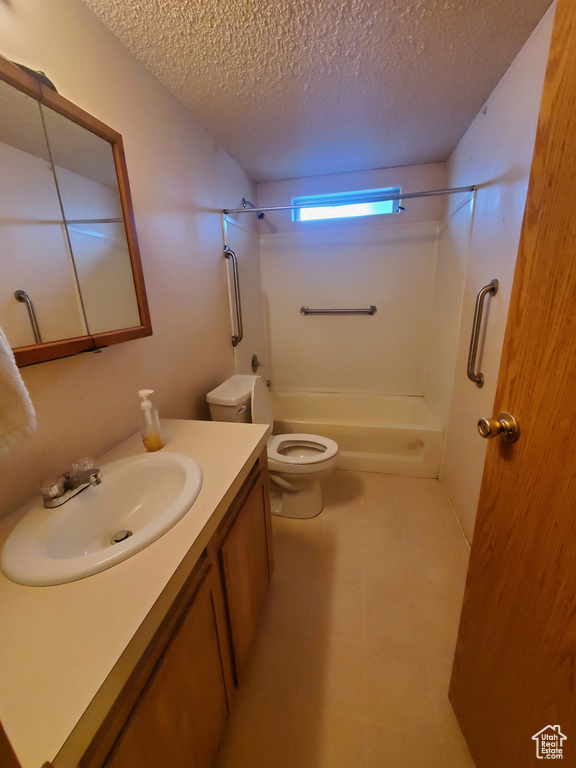 Full bath featuring vanity, toilet, a textured ceiling, and shower / washtub combination