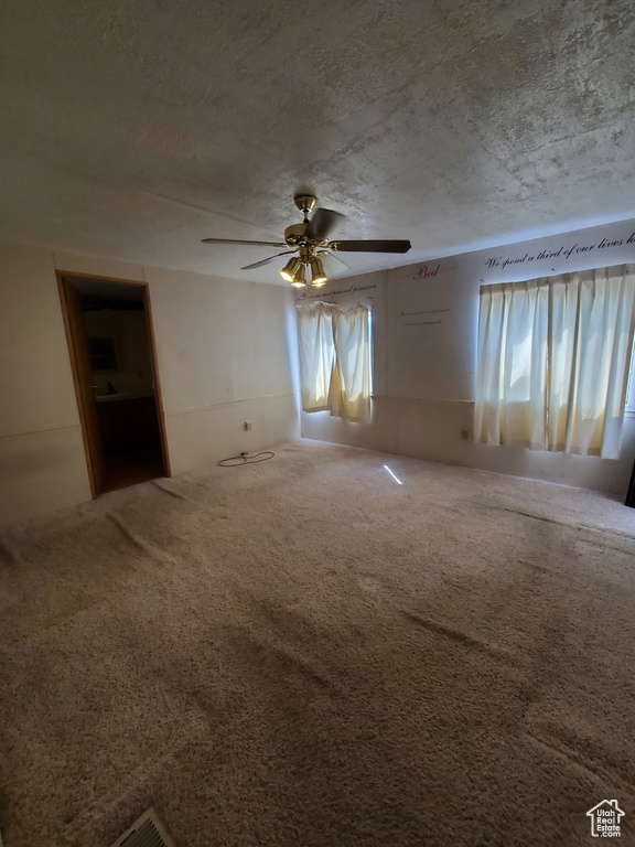 Unfurnished room featuring a textured ceiling, carpet, and ceiling fan