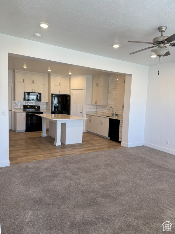 Kitchen featuring light countertops, backsplash, open floor plan, and black appliances
