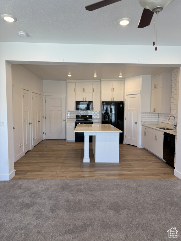 Kitchen with a sink, tasteful backsplash, black appliances, ceiling fan, and a kitchen island