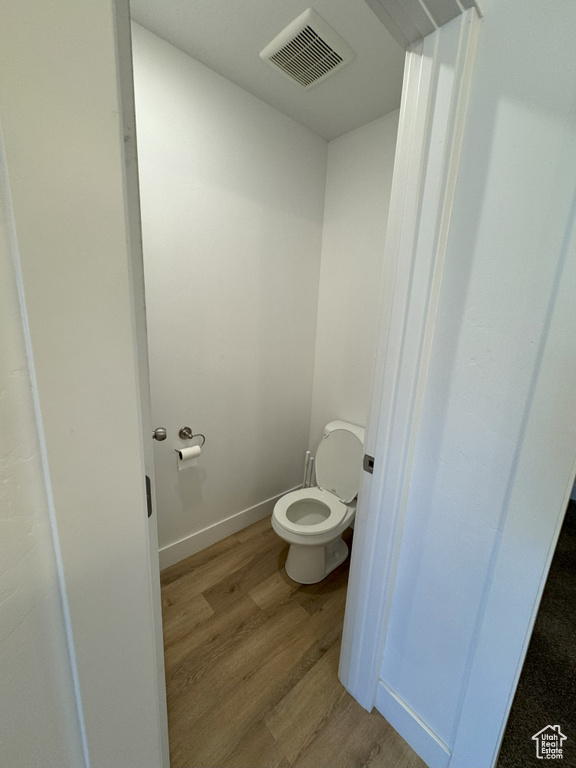 Bathroom featuring toilet, visible vents, and wood finished floors