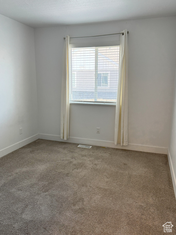 Unfurnished room with carpet flooring, visible vents, and baseboards