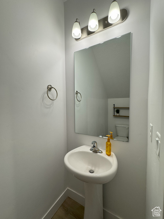 Bathroom with wood finished floors, vaulted ceiling, and baseboards