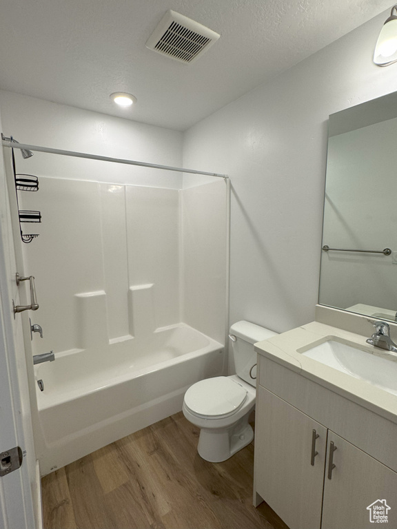 Full bathroom with toilet, shower / washtub combination, visible vents, and wood finished floors
