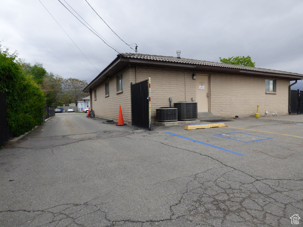 View of home's exterior with uncovered parking, brick siding, and central AC