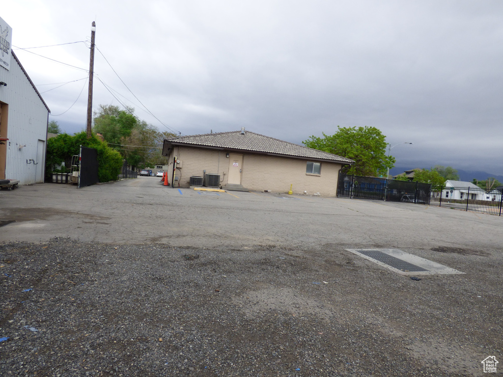 View of home's exterior featuring uncovered parking, fence, a tile roof, and cooling unit