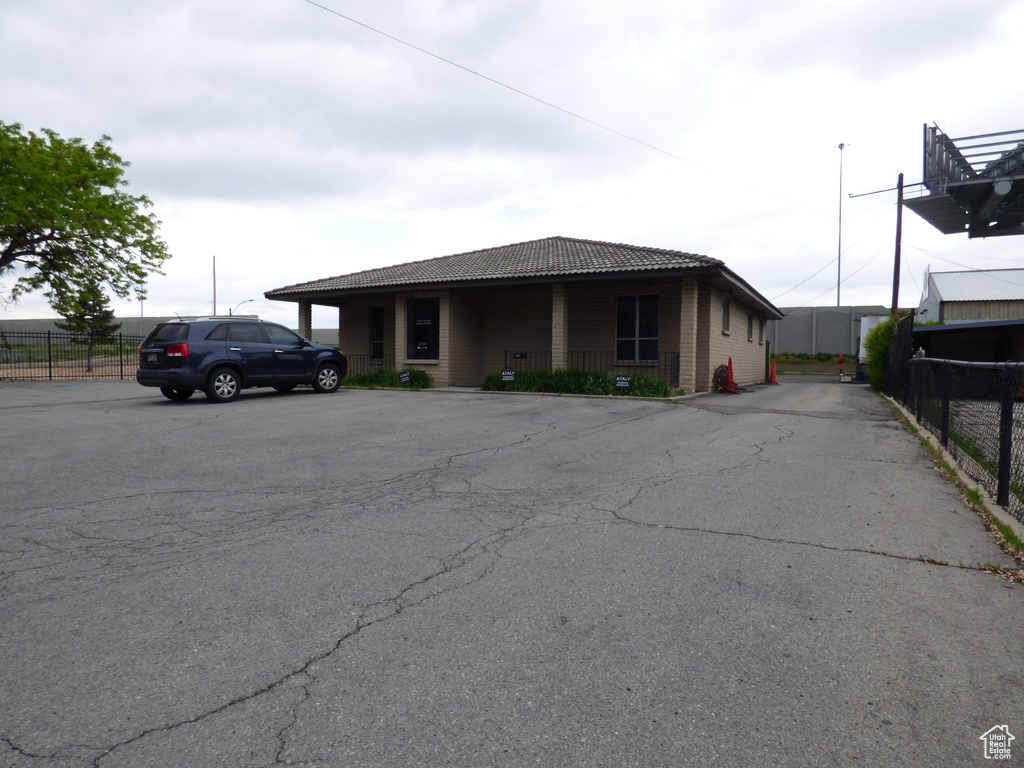View of front of property with a tile roof, fence, and uncovered parking