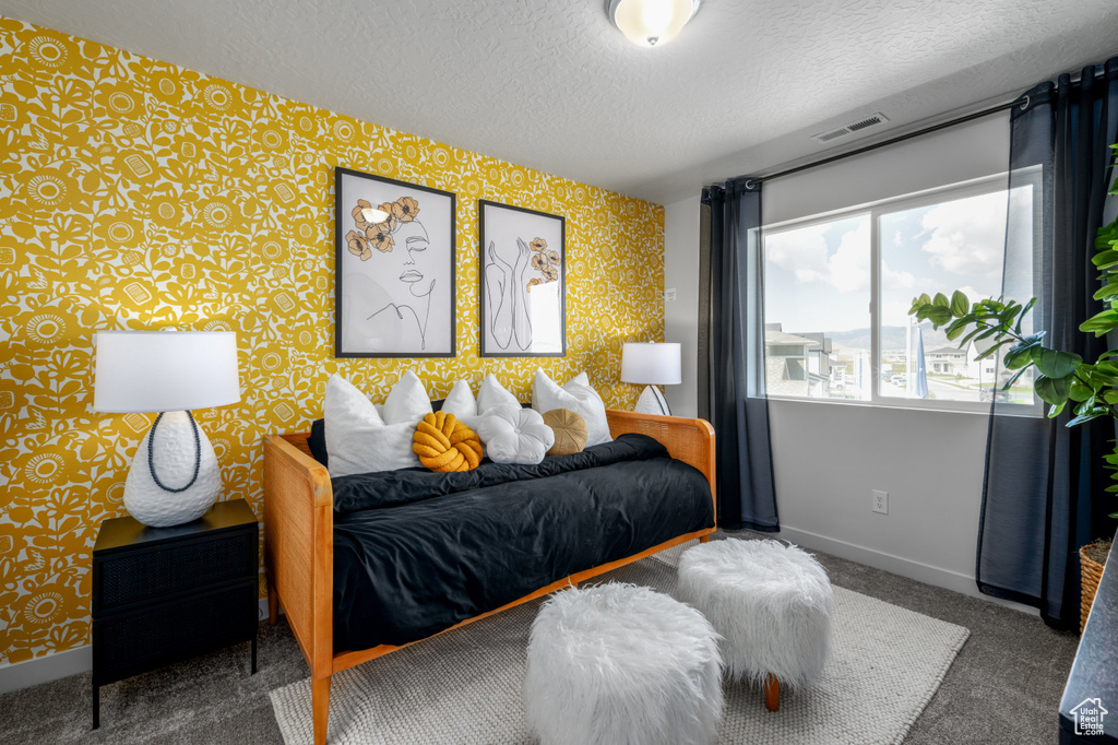 Carpeted bedroom featuring a textured ceiling, baseboards, wallpapered walls, and visible vents