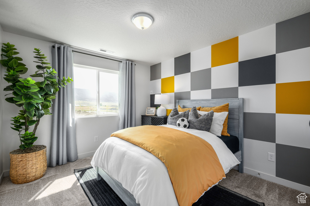 Bedroom with a textured ceiling, light carpet, baseboards, and visible vents