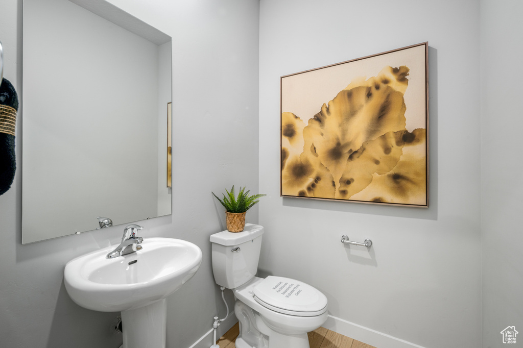 Half bath with toilet, baseboards, and a sink