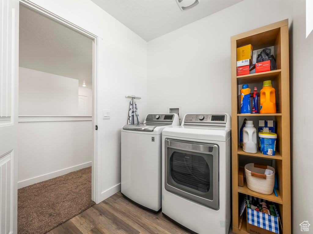 Clothes washing area featuring baseboards, laundry area, wood finished floors, and washer and clothes dryer