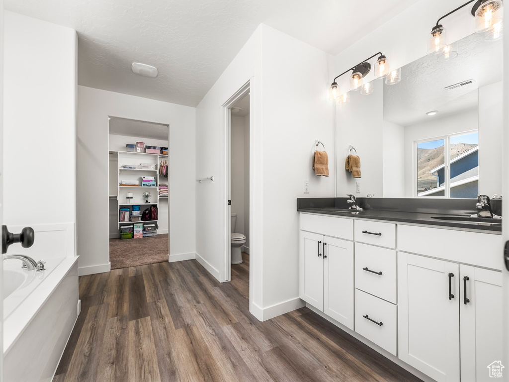 Full bathroom with a sink, toilet, visible vents, and wood finished floors
