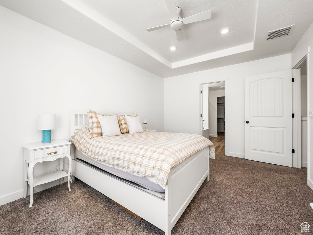 Carpeted bedroom with a ceiling fan, a tray ceiling, visible vents, baseboards, and recessed lighting
