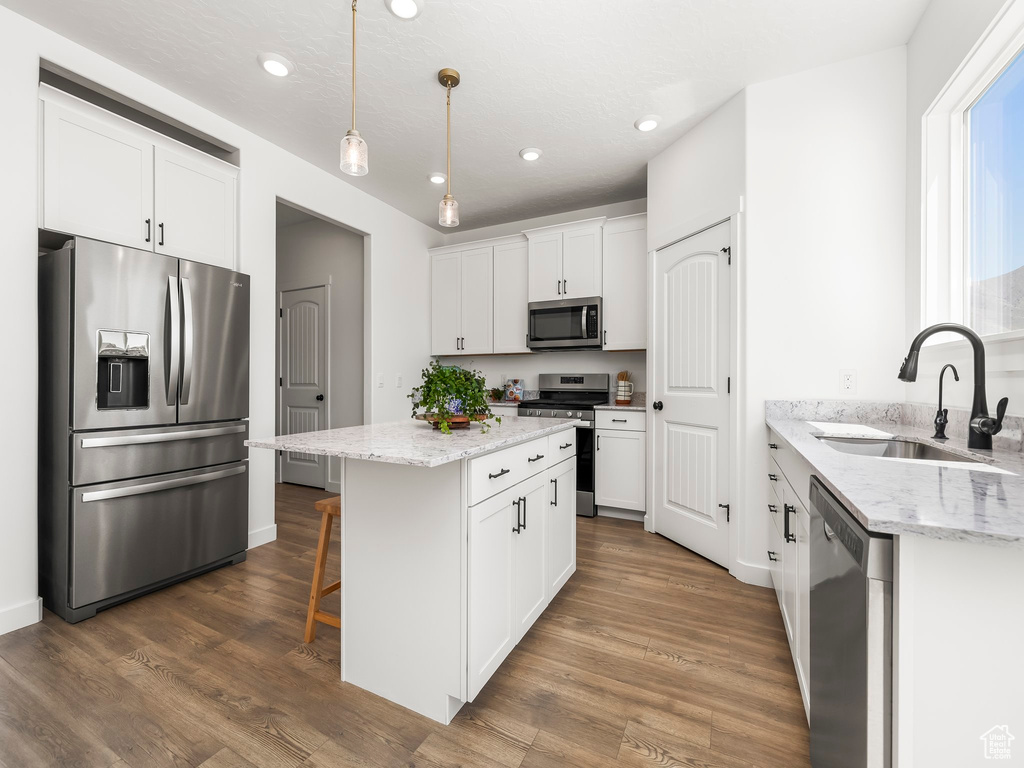 Kitchen featuring recessed lighting, appliances with stainless steel finishes, a kitchen island, and a sink