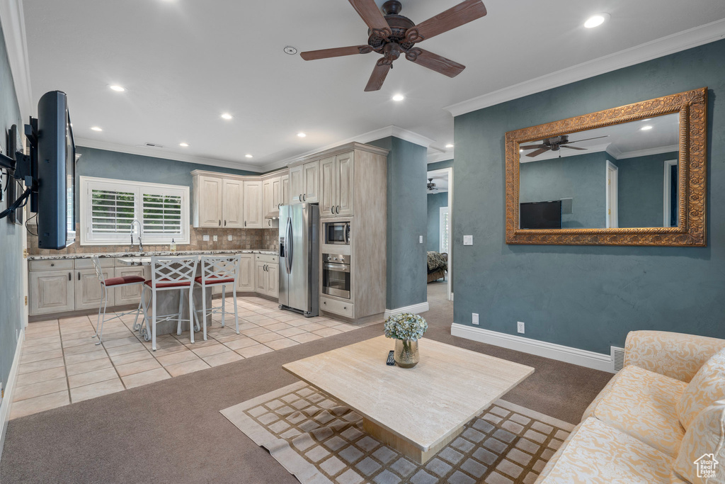 Living area featuring recessed lighting, light tile patterned floors, ornamental molding, ceiling fan, and light carpet