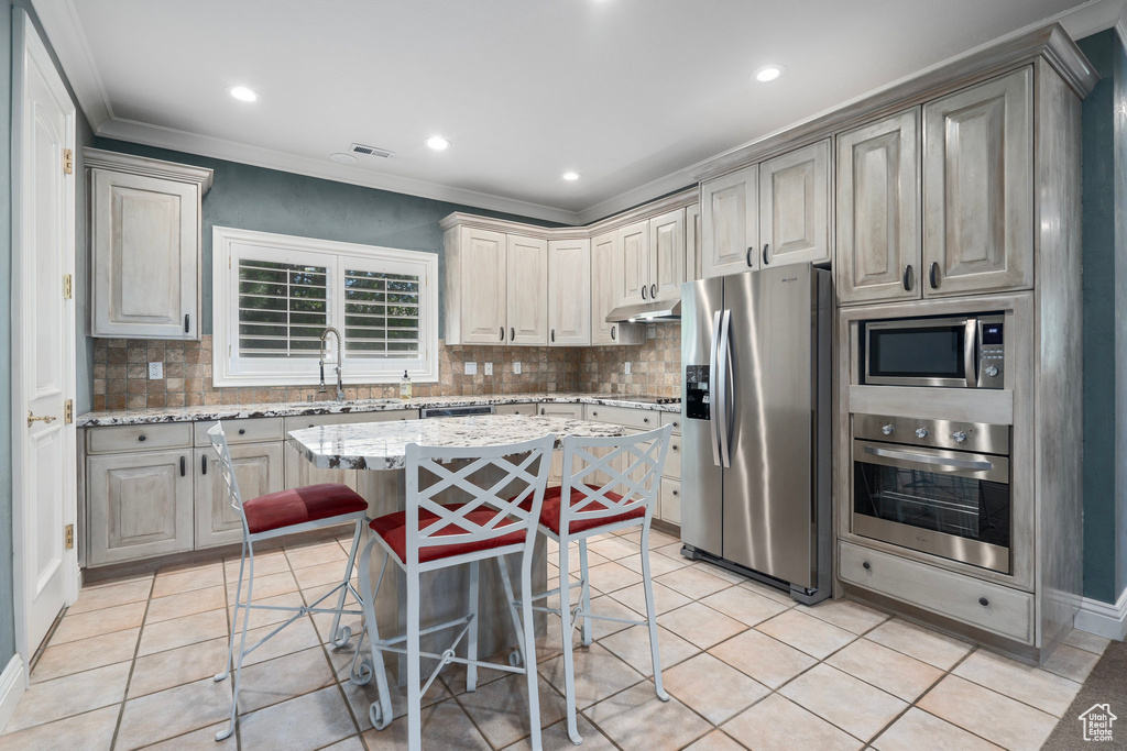 Kitchen with under cabinet range hood, stainless steel appliances, tasteful backsplash, and a sink