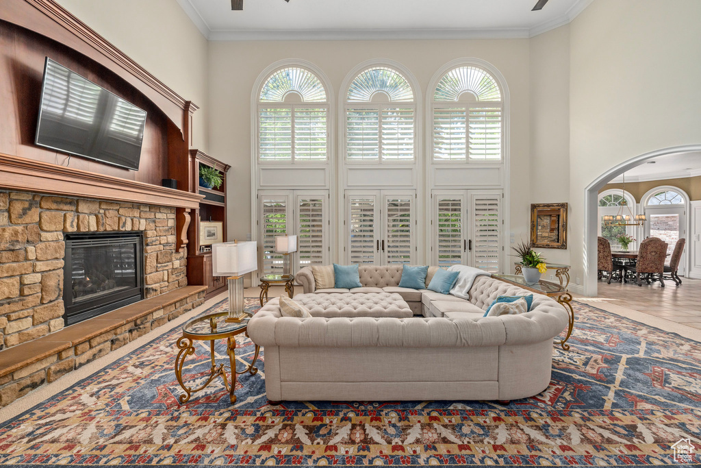 Living area with a fireplace, crown molding, a towering ceiling, and a wealth of natural light