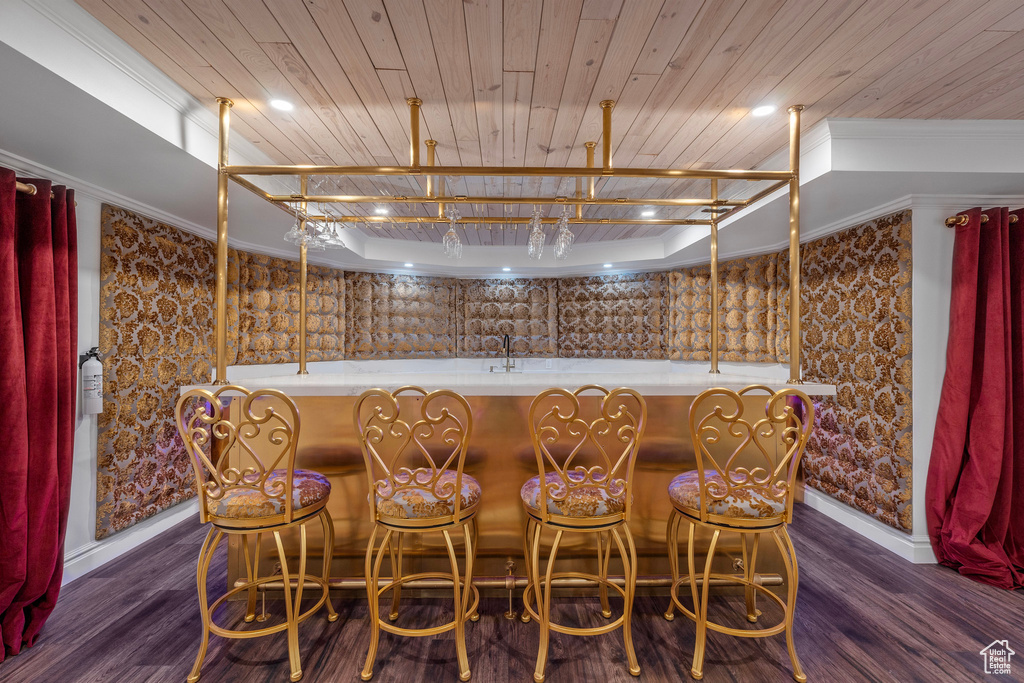 Bar featuring baseboards, dark wood-style flooring, a community bar, and wooden ceiling