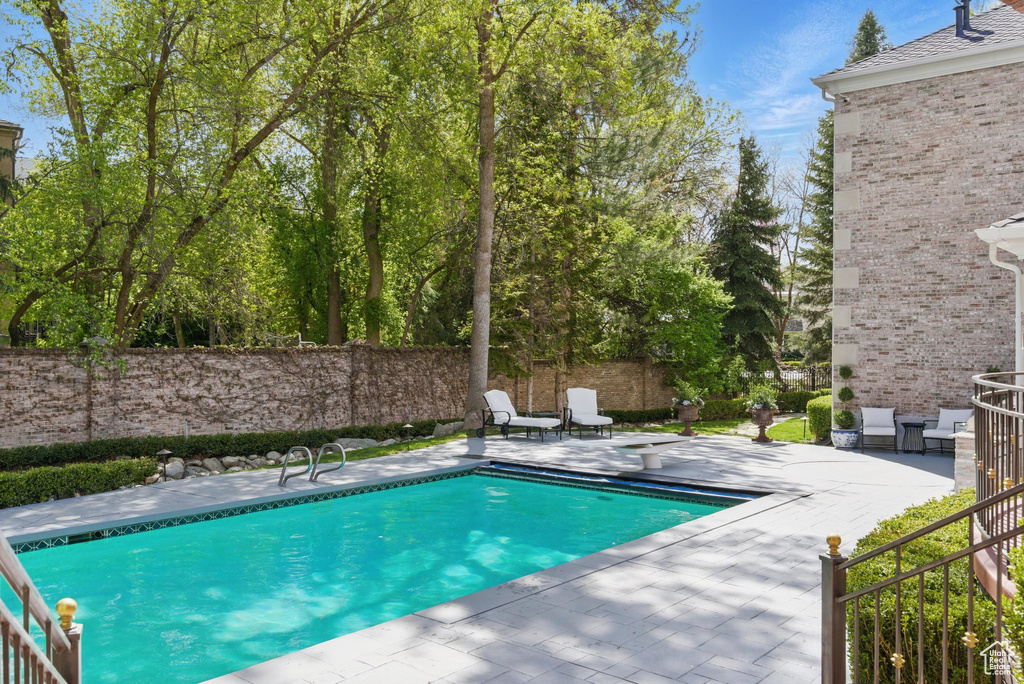 View of pool with a patio area, fence, and a fenced in pool
