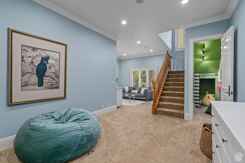 Living area with ornamental molding, recessed lighting, and light colored carpet