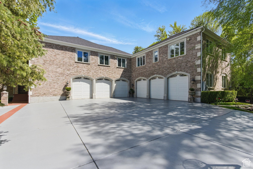 View of front of house with driveway, brick siding, and a garage
