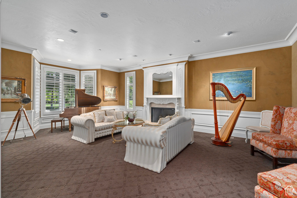 Living room with a fireplace, ornamental molding, a decorative wall, and dark carpet