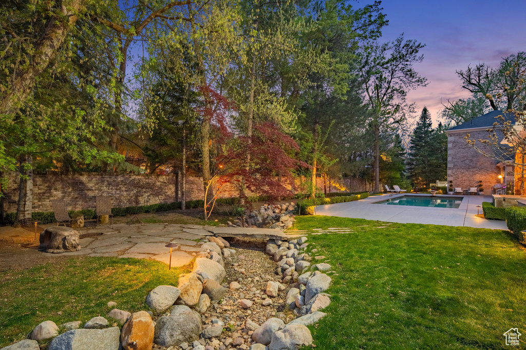 Yard at dusk featuring a patio and an outdoor pool