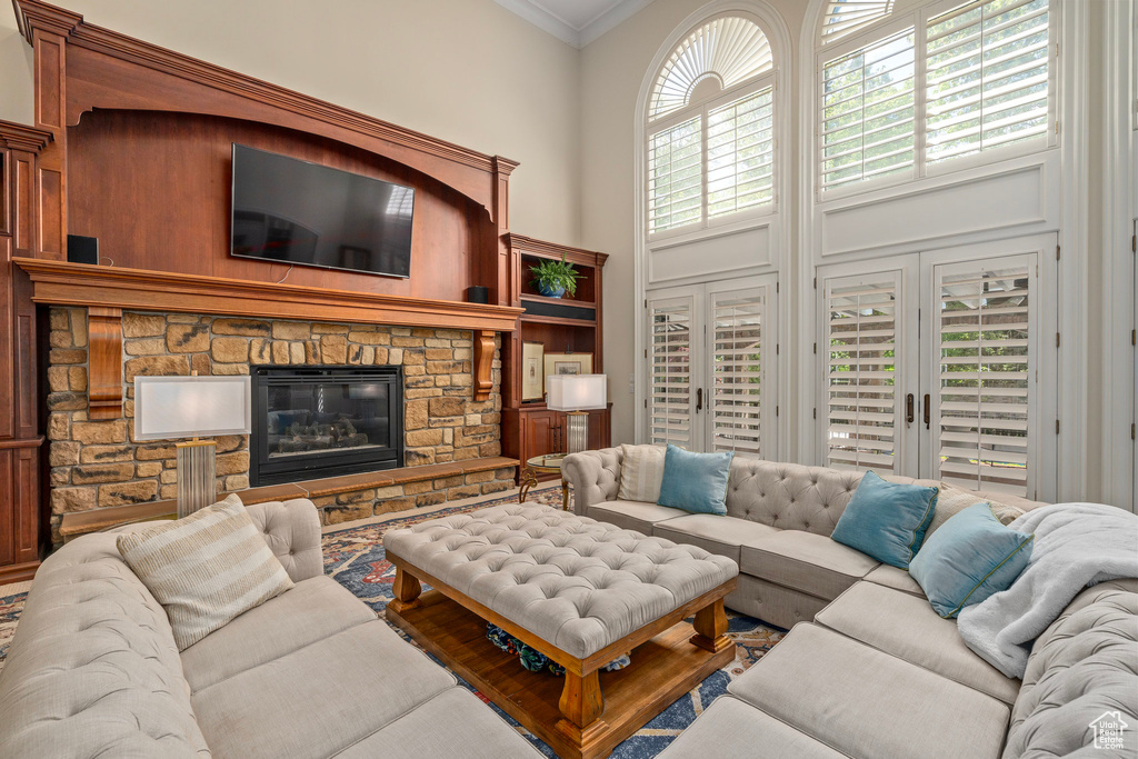 Living area with a fireplace, ornamental molding, and a towering ceiling