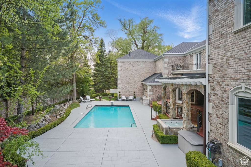 Pool with a fenced backyard, a patio area, and a diving board