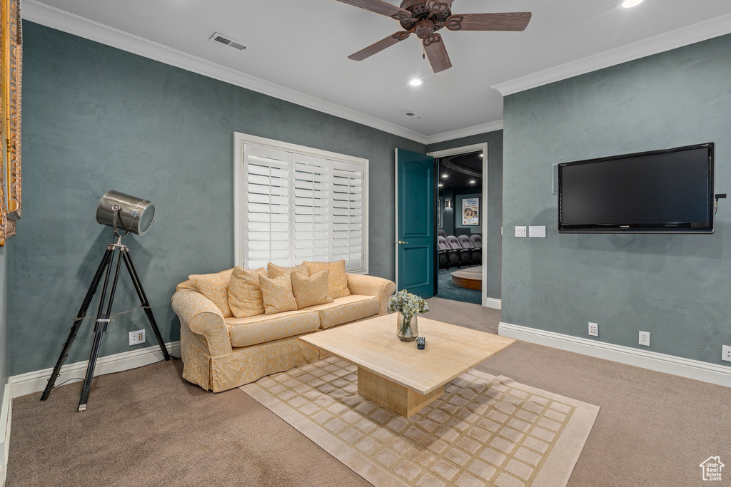 Carpeted living room featuring a ceiling fan, visible vents, baseboards, ornamental molding, and recessed lighting