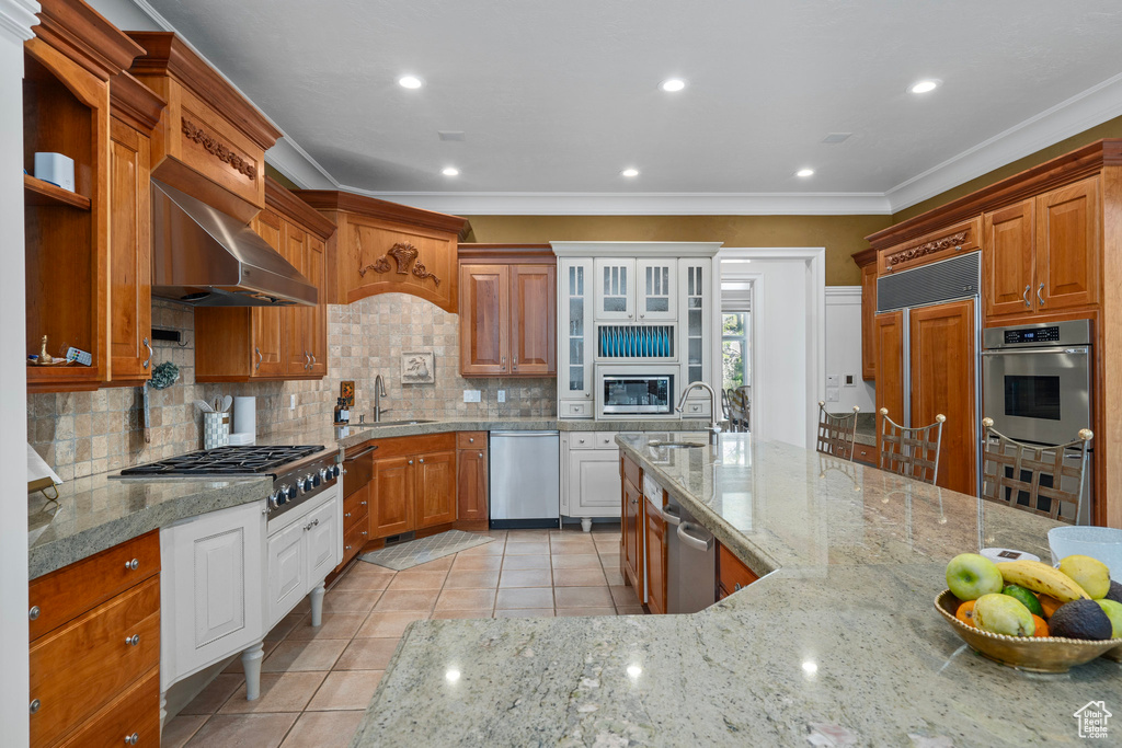 Kitchen featuring built in appliances, ornamental molding, light tile patterned floors, and a sink