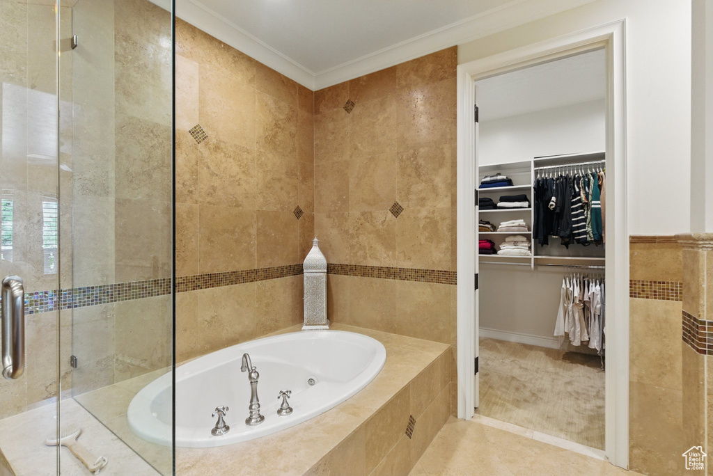 Bathroom featuring tile walls, ornamental molding, a shower stall, a walk in closet, and a bath