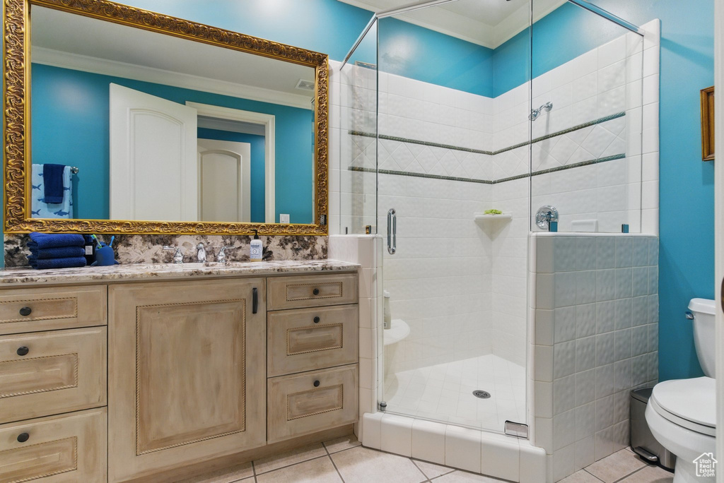 Bathroom featuring toilet, tile patterned flooring, vanity, and a stall shower