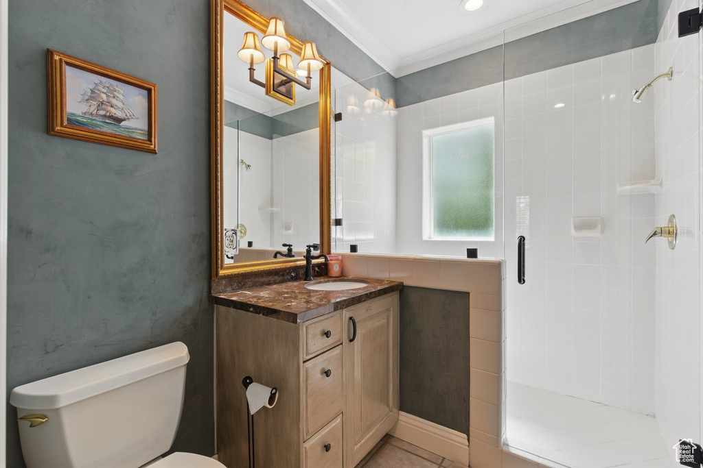 Bathroom with toilet, tile patterned floors, crown molding, a shower stall, and vanity