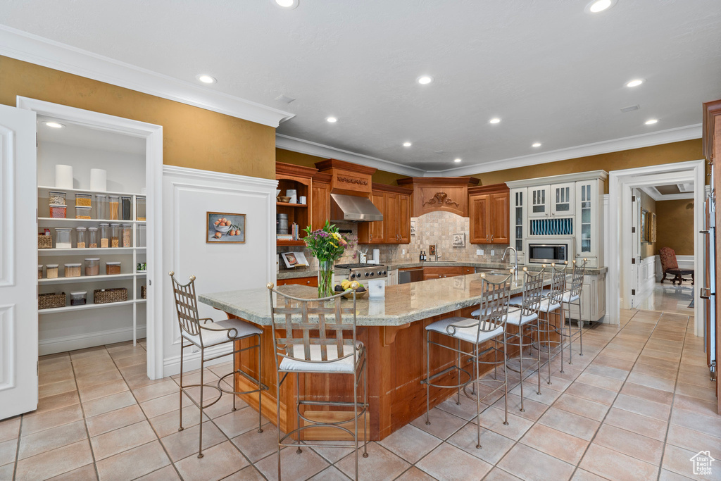 Kitchen with recessed lighting, wall chimney range hood, appliances with stainless steel finishes, and crown molding