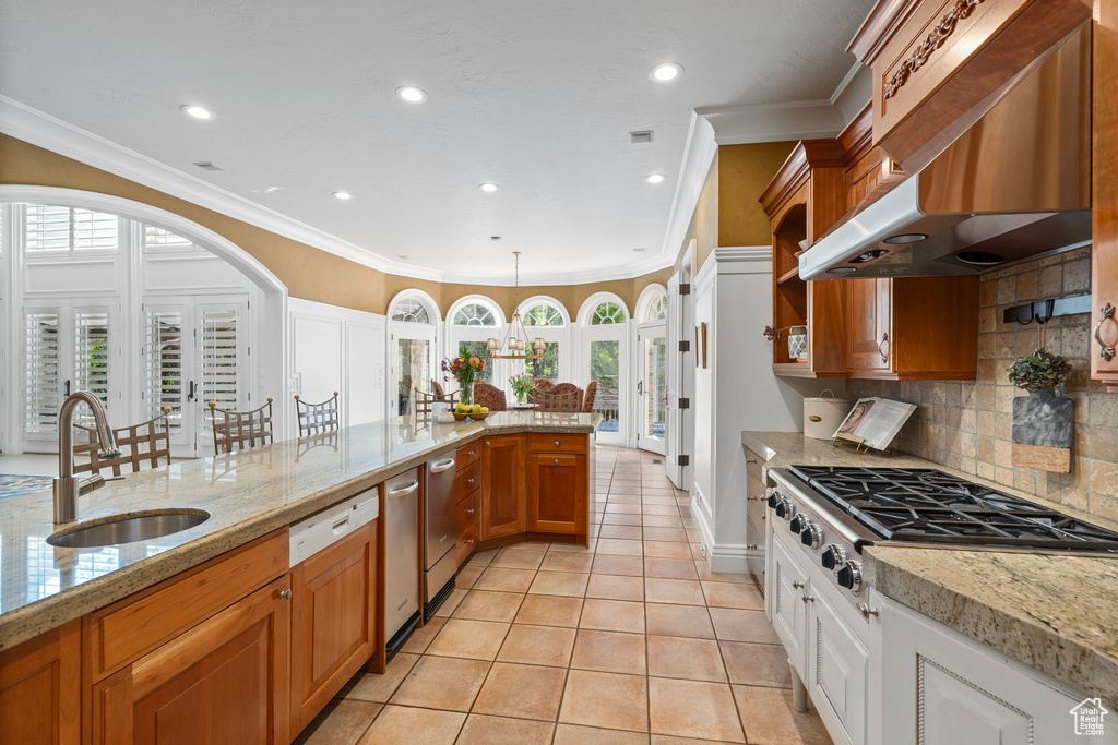 Kitchen featuring light tile patterned floors, a sink, range hood, stainless steel gas stovetop, and tasteful backsplash