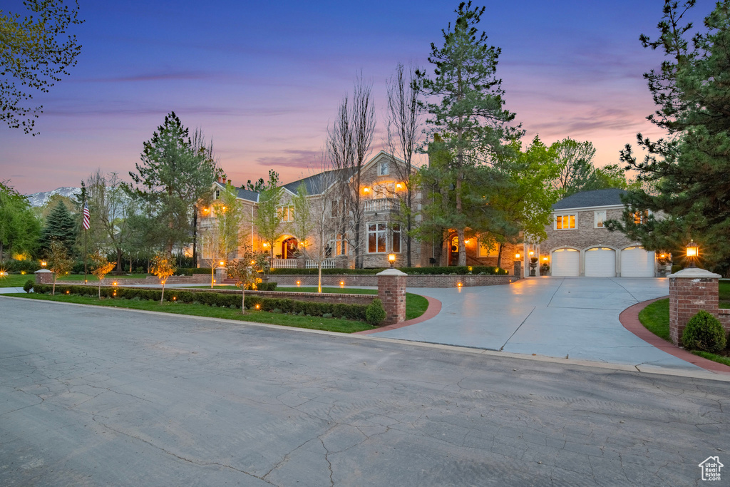 View of front of property with stone siding, an attached garage, and curved driveway