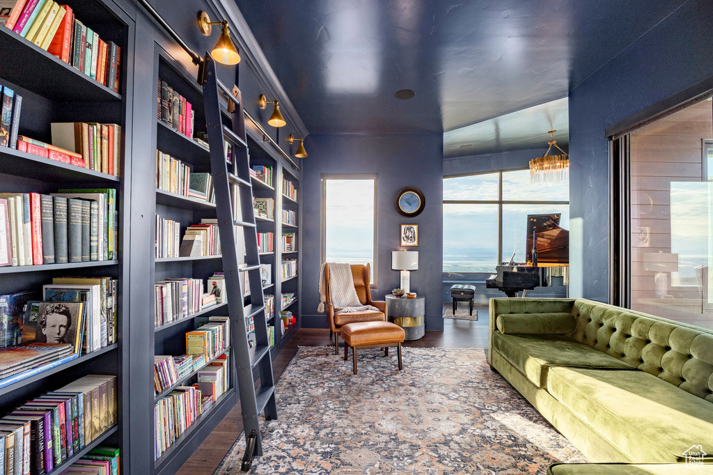Living area featuring wall of books, built in shelves, and wood finished floors