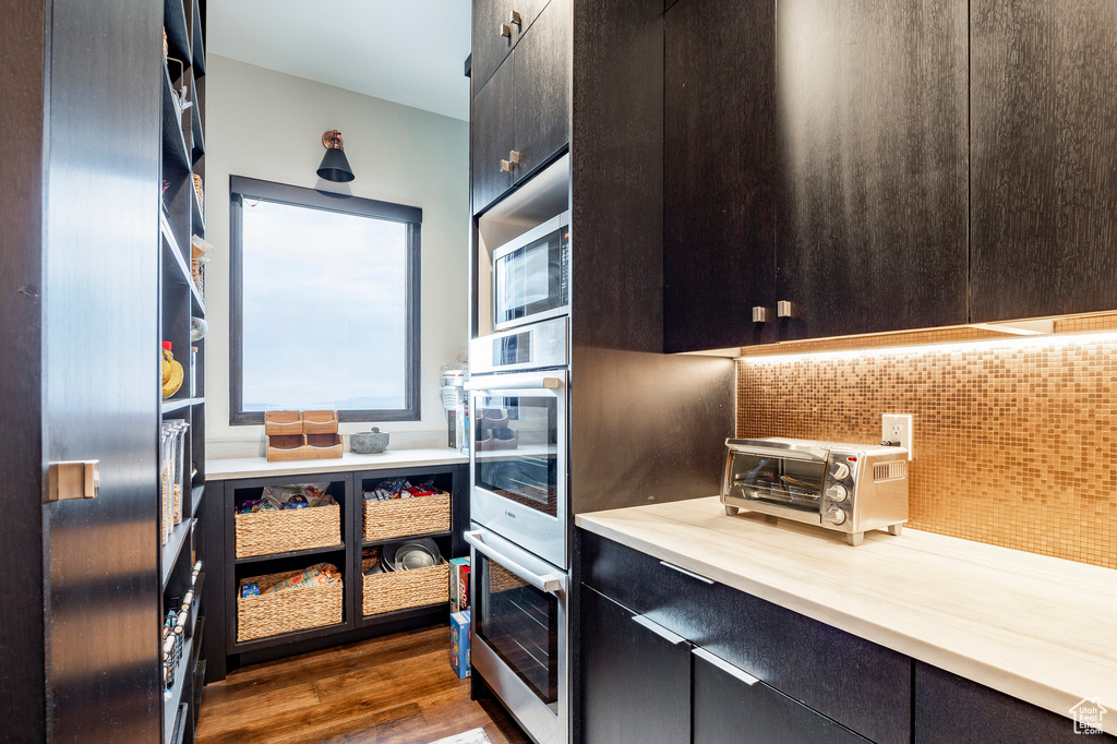 Kitchen featuring a toaster, backsplash, light countertops, dark wood-style floors, and appliances with stainless steel finishes